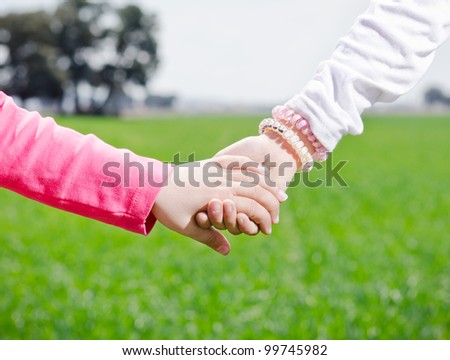 two girls holding hands on a green background of nature