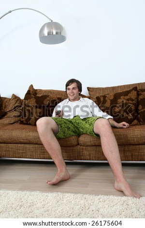 Young cute male relaxing on couch and watching TV