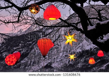glowing Chinese lanterns hanging down from a tree with mountains in the background