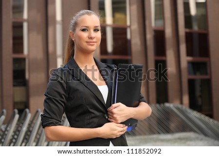 Business woman with folders on the background of business building