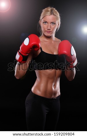 Young woman wearing boxing gloves isolated on black