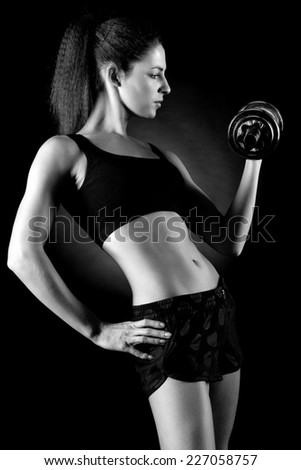 beautiful sporty muscular woman working out with dumbbells . Black and white photo