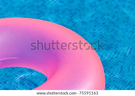 Floating ring on blue water swimpool with waves reflecting in the summer sun..