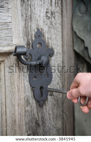 Unlocking an old, heavy castle door with a huge key.