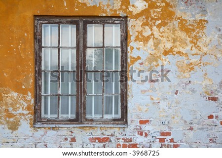 Old, brown casement window with bars and peeling yellow wall.