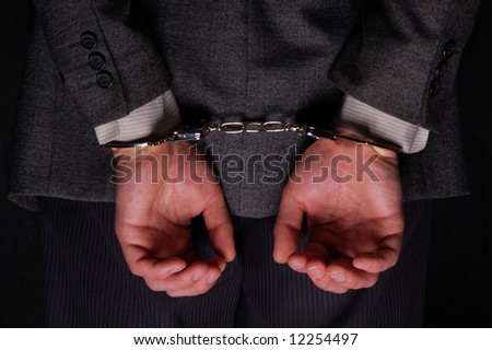 Arrested businessman handcuffed hands at the back Save to a lightbox 
