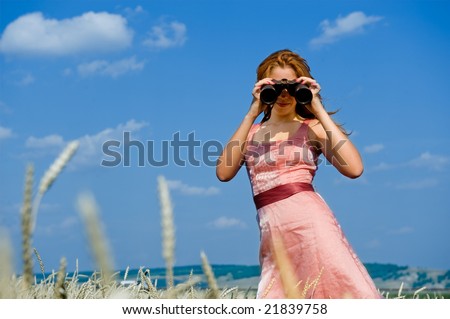 Search. Woman looking through binoculars with a blue sky as background