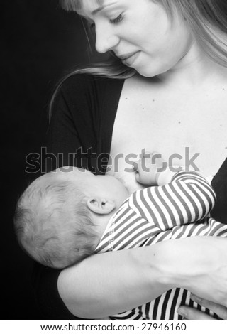 Mother breast feeding her little son. Picture of happy mother on black background