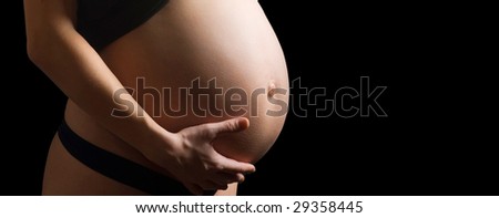 Close-up pregnant belly. Nine month. Isolated over black background