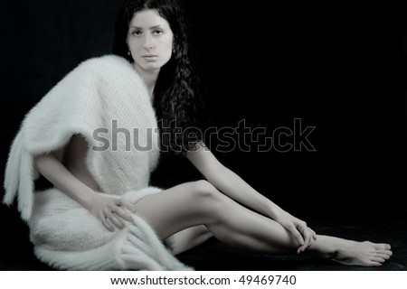 Picture of beautiful young woman over black background.Big scarf wrapped around a beautiful woman body. Horizontal view.