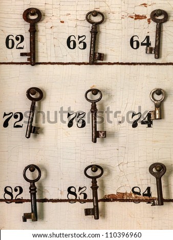 Old keys with numbers hanging on a weathered wall of an old hotel