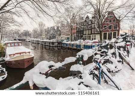 Bicycles covered with snow on a bridge during winter in Amsterdam
