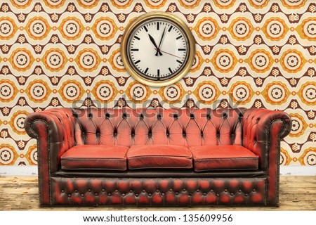 Retro styled image of an old sofa and clock against a vintage wallpaper wall with flower print