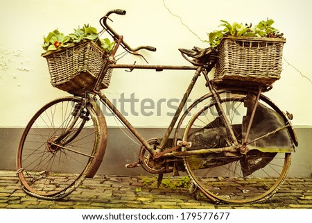 Retro styled image of an old broken rusty bicycle with baskets
