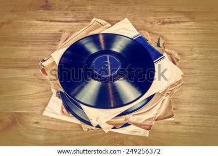 Retro styled image of a collection of old vinyl record lp's with sleeves on a wooden background