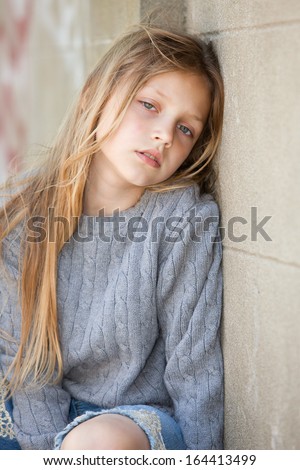 sad little girl sitting against the wall