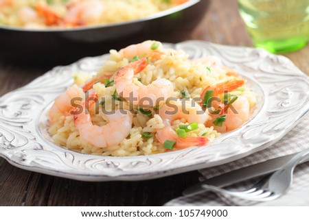 Risotto with shrimps and green onion on a rustic table