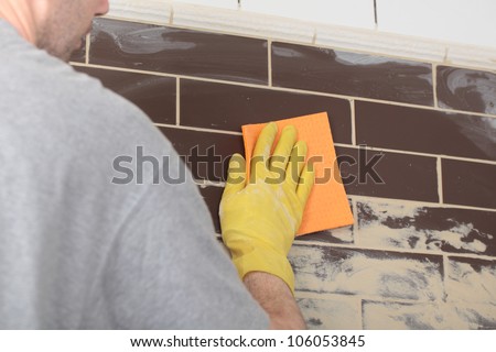 Contractor grouting ceramic tiles on a wall