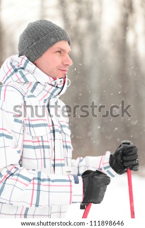 Adult man with Nordic walking poles under snowfall