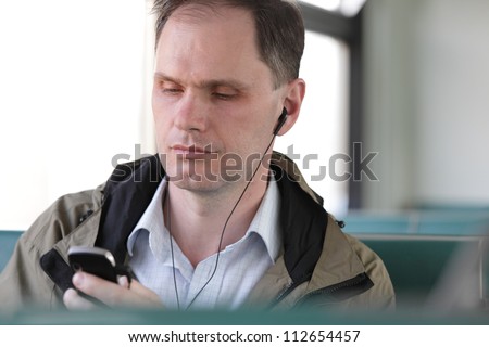 Man in commuter train listening music over his mobile phone