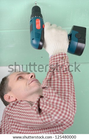Man installing drywall using cordless drill