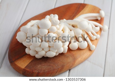Bunch of raw Shimeji mushrooms also known as white beech mushrooms on a wooden cutting board