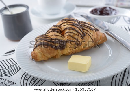 Breakfast with croissant, butter, yogurt, jam, and coffee