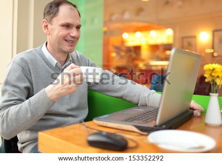 Man with laptop drinking coffee in a cafe