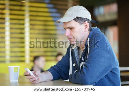 Mature man with smartphone in a fast food restaurant