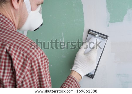 Contractor sanding the drywall mud using sand trowel
