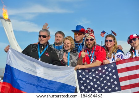 SOCHI, RUSSIA - FEBRUARY 12, 2014: Russian and American fans with flags in the Olympic Park during XXII Winter Olympics against Olympic flame. Russia hosts the second Olympic Games in history