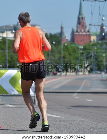 MOSCOW, RUSSIA - MAY 18, 2014: Unidentified runner on the distance of Moscow Half Marathon against Kremlin towers. It is the second race of the Moscow Marathon race series
