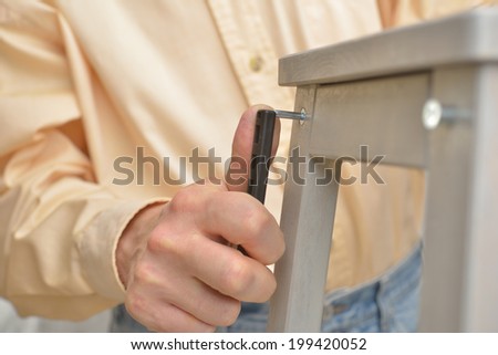 Man assembling the step stool. Selective focus on the Allen key