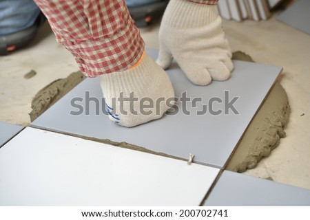 Tiler installs ceramic tiles on a floor