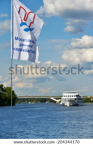 MOSCOW, RUSSIA - JULY 4, 2014: Flag of Moscow River Shipping Company against the ship on the Moscow canal. Founded in 1857, now the company manages 26 enterprises with more than 5700 employees