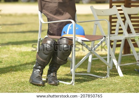 TSELEEVO, MOSCOW REGION, RUSSIA - JULY 26, 2014: Equestrian helmet and riding boots with kneepads on the folding chair during the British Polo Day. It was the second British Polo Day in Russia