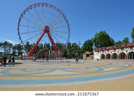 KHARKOV, UKRAINE - JUNE 10, 2014: People resting in front of the Ferris wheel in the Central park named after M. Gorky. The Ferris wheel is 55 m tall, and is the largest in Ukraine