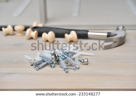 Fasteners, buttons, and hammer against parts of wooden furniture