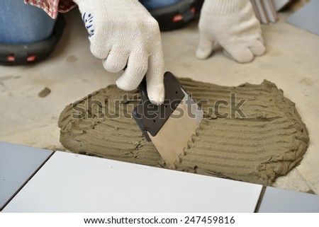 Worker spreading cement during tiled floor installation