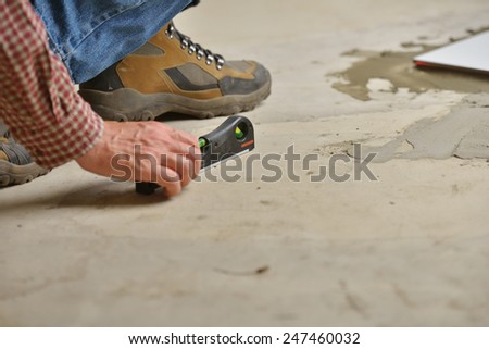 Worker checking the surface using spirit level during the tiled floor installation