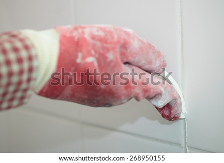 Contractor grouting ceramic tiles on a wall