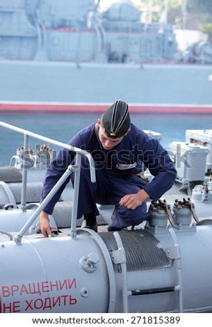 SEVASTOPOL, CRIMEA, UKRAINE - AUGUST 17, 2012: Seaman performs maintenance of  the torpedo tube on the Russian frigate \