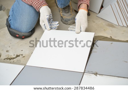 Worker installs ceramic tiles on a floor