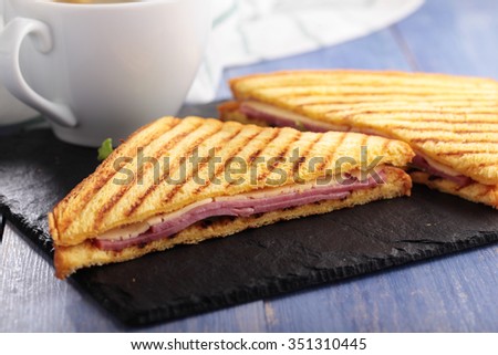 Sandwiches with ham, cheese, lettuce, grilled toasts, and a cup of coffee