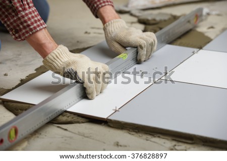 Tiler installs ceramic tiles on a floor