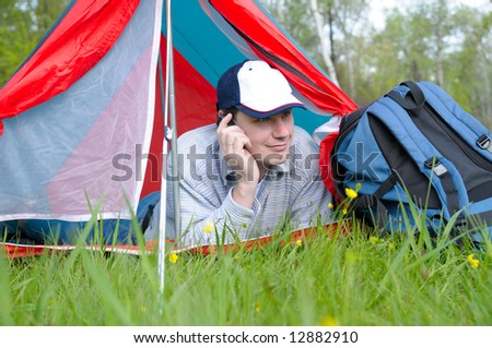 man resting in forest and talking by phone