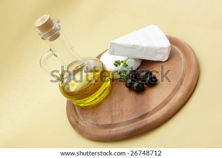 Delicious cheese, olives and olive oil on a wooden cutting board