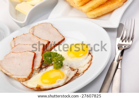 American breakfast with fried eggs, bacon, toasts, butter, and juice
