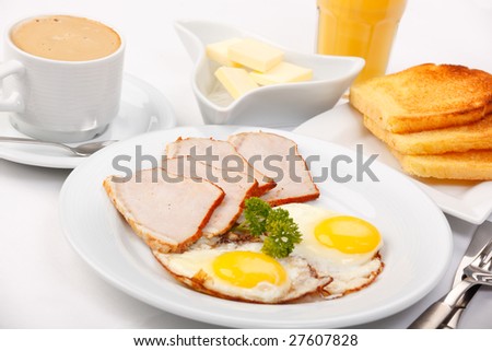 American breakfast with fried eggs, bacon, toasts, butter, juice, and coffee