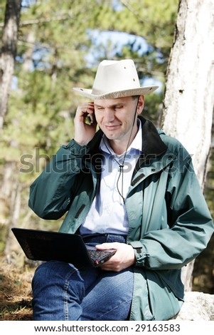 Hiker with laptop and mobile phone in forest